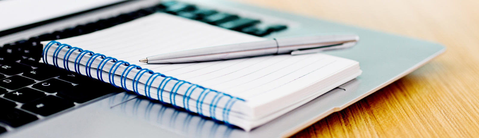 a pen on top of a notepad next to a laptop